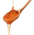 Honey dripping from a wooden honey dipper isolated on white back Royalty Free Stock Photo