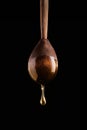 Honey dripping from a wooden spoon on black background. A drop of honey glows in the sun. Royalty Free Stock Photo
