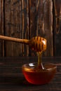 Honey flows from a stick into a jar. Rustic sweet photo, wooden background, copy space