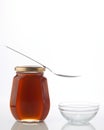 Honey in a glass bottle with spoon on the top isolated white background