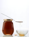 Honey in a glass bottle with spoon on the top isolated white background