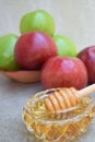 Honey in a glass bowl and colorful apples in the background