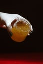 Honey in a glass jar close up on a black background on a red wooden table. pour honey with a stick honey dipper Royalty Free Stock Photo