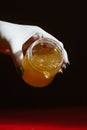 Honey in a glass jar close up on a black background on a red wooden table. pour honey with a stick honey dipper Royalty Free Stock Photo