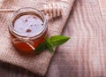 Honey in a glass jar, honey spoon and mint leaves on the wooden
