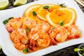 Honey Glazed Shrimp with orange slices, spices and sunflower sprouts on white plate on bamboo background
