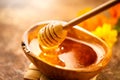 Honey. Healthy organic thick honey dripping from the honey dipper in wooden bowl. Sweet dessert