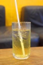 Honey lemon green tea with ice in glass with black drinking straw on table with blurred background Royalty Free Stock Photo