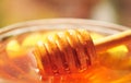 Honey macro with wooden honey dipper in the glass jar
