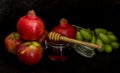 Honey, pomegranate, and apples on the black table. Jewish New Year Rosh Hashanah postcard