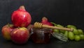 Honey, pomegranate, and apples on the black table. Jewish New Year Rosh Hashanah postcard