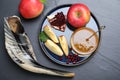 Honey, pomegranate, apples and shofar on black table, flat lay. Rosh Hashana holiday