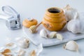 A close up of a honey pot and dipper surrounded by garlic cloves and a garlic press. Honey garlic concept. Royalty Free Stock Photo