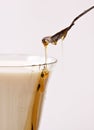 Honey poured into milk with spoon Royalty Free Stock Photo