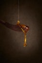 Honey pouring on wooden spoon and dripping from spoon. Brown background. Royalty Free Stock Photo