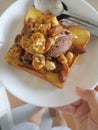 The honey toast with popcorn, chocolate ice-cream and mix nuts topping on white dish at home.