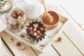 Honey in the wooden bowl, hazelnuts and jar with milk on the wooden tray Royalty Free Stock Photo