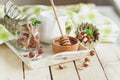 Honey in the wooden bowl, mint leaves, hazelnuts and jar with milk on the wooden tray