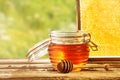 Honeycomb behind glass resealable jar of honey