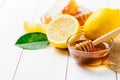 Honeycomb on dish with honey dipper with lemons on white wood background