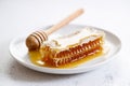 Honeycomb and honey dipper in white dish