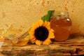 Honeycomb in a wooden frame decorated with sunflower and glass jar of honey on a wooden background