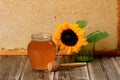 Honeycomb in a wooden frame decorated with sunflower and glass jar of honey on a wooden background