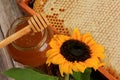 Honeycomb in a wooden frame decorated with sunflower and glass jar of honey on a wooden background