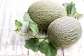 Honeydew melons with sprig on white wooden table Royalty Free Stock Photo