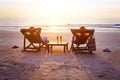 Honeymoon travel, silhouettes of happy couple relaxing in deck chairs on the beach