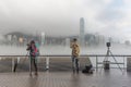 Tourist taking photo of foggy landscape of Victoria Harbor in Hong Kong city