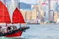 Hong Kong, China - May, 2019: Old wooden tourist junk ferry boat in Victoria Harbor against famous Hong Kong island view with Royalty Free Stock Photo