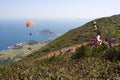 Hong Kong: hikers watch paraglider take off, ocean in background