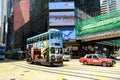 Colorful double-decker tram and red taxi in Hong Kong.