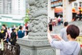 HONGKONG, China - APRIL 2018: occasional female visitor of wong tai sin temple in Hong Kong taking picture of stone dragon