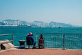Fisher man or woman with fishing rod sitting on coast with HongKong skyline background