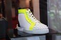Fashionable white sneakers with toe cap studs and neon yellow trim by luxury designer Christian Louboutin