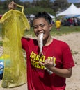 Honolulu, Hawaii, USA - 2022-08-20 - Shaka Filming Hukilau - boy holds the first fish from the nets in his mouth in