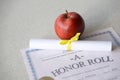 A honor roll lies on table with small scroll and red apple. Education documents Royalty Free Stock Photo