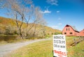 Honor system sign in rural New England beside an American style red barn by a river