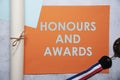 Honours and awards text on orange and baby blue background flat lay concept