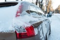 The hood and doors of the car are covered with snow and ice after a snowfall. Parked cars are coated with snow. Big frosts and a Royalty Free Stock Photo