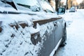 The hood and doors of the car are covered with snow and ice after a snowfall. Parked cars are coated with snow. Big frosts and a Royalty Free Stock Photo