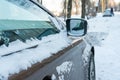 The hood and doors of the car are covered with snow and ice after a snowfall. Parked cars are coated with snow. Big frosts and a Royalty Free Stock Photo