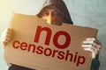 Hooded activist protestor holding No Censorship protest sign