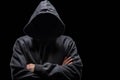 Hooded anonymous hacker with arms crossed, isolated on black background