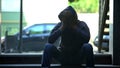 Hooded black male teenager closing face with hands, depression problem