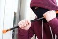 Hooded burglar forcing window to rob in the house Royalty Free Stock Photo