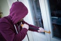 Hooded burglar forcing window to rob in the house Royalty Free Stock Photo