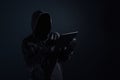 Hooded computer hacker with obscured face using digital tablet